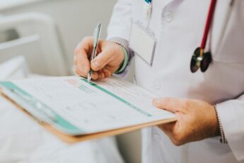 A Doctor Filling Out A Patient Form