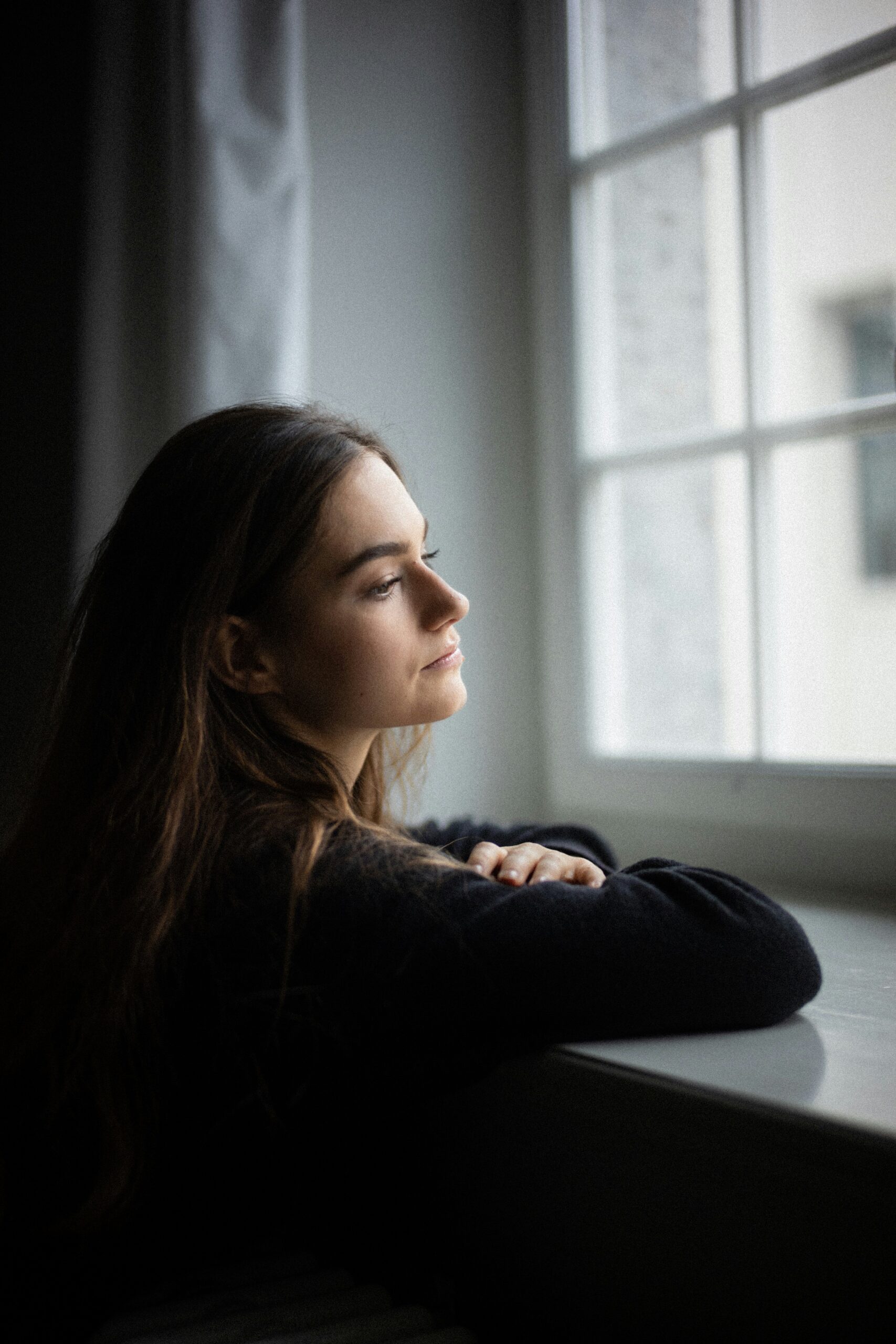 Pregnant Woman looking out window considering her pregnancy options